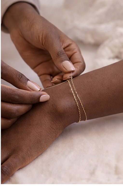 A delicate gold chain being fitted around a wrist